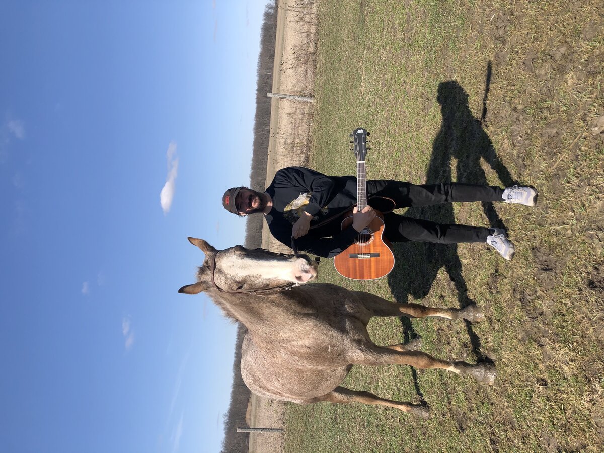 Chris with guitar in open field